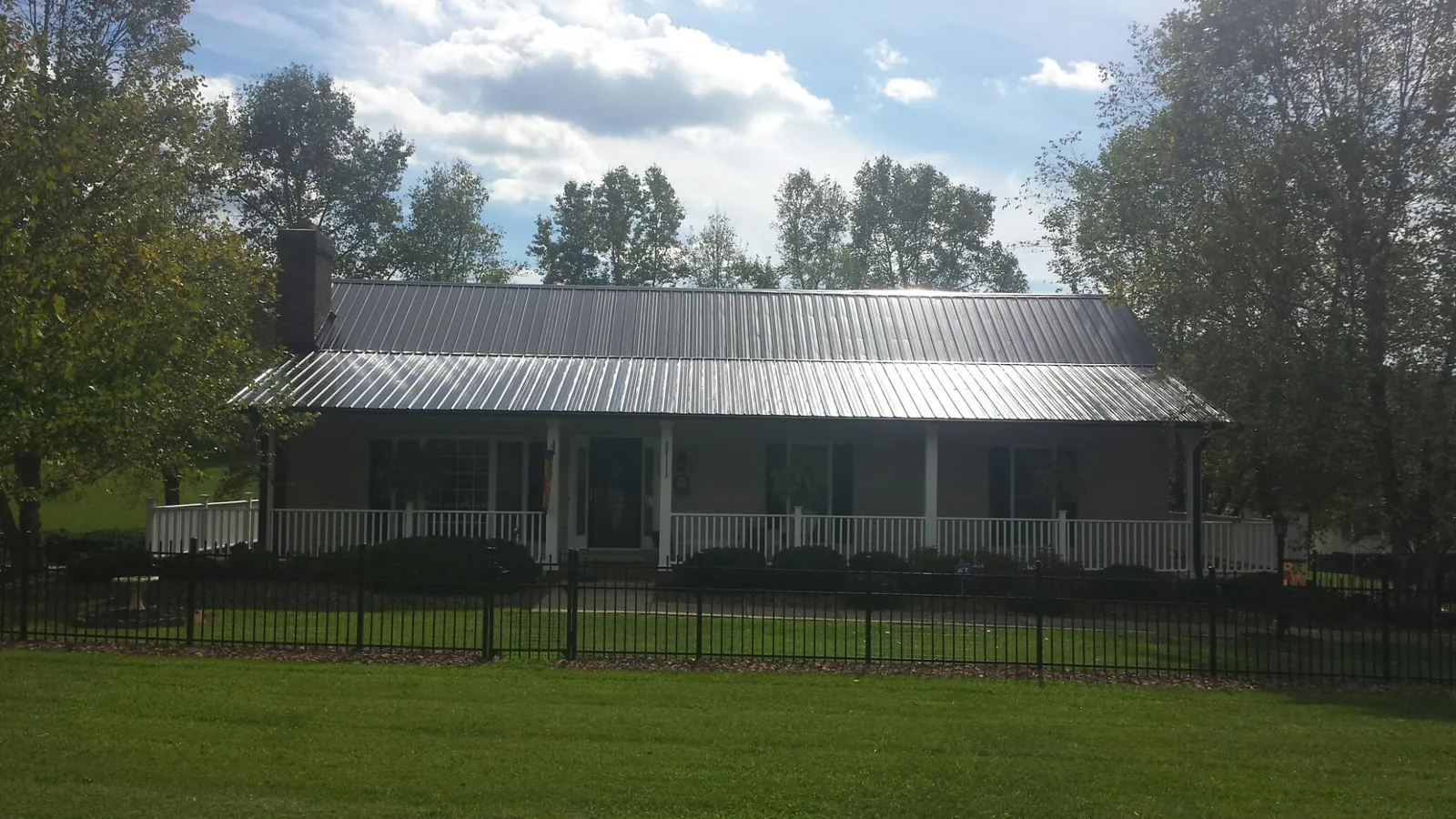 Gray metal roof on a brick ranch with a full width front porch — Gutter Guard Installation work by our crew in Keystone