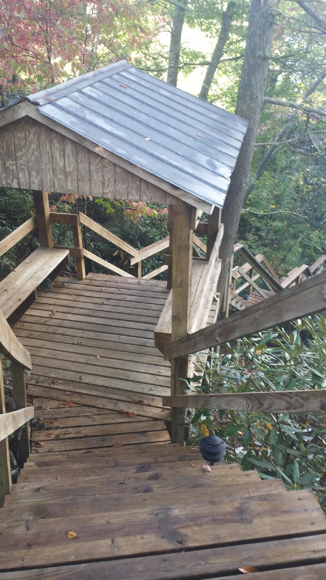 Metal roofed shelter over wooden steps on a wooded walkway — Skylight Repair & Installation work by our crew in Keystone