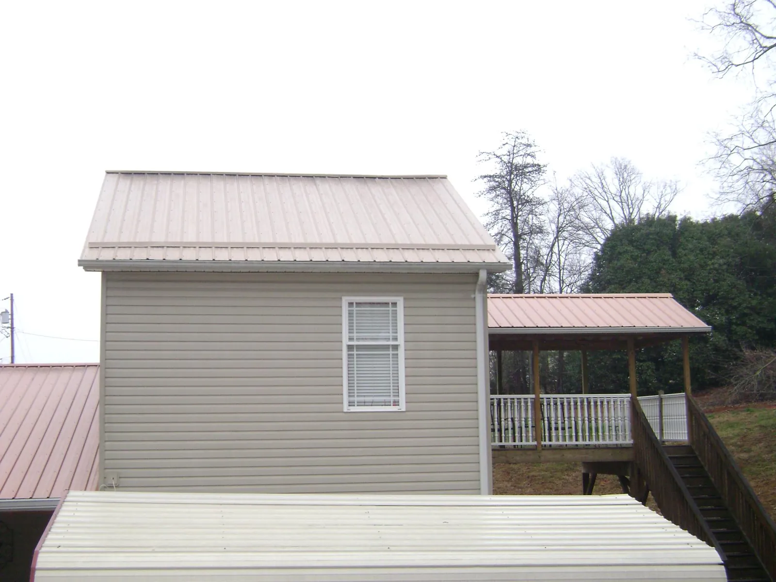 Tan metal roofs on a two story addition and attached porch, from a Roof Replacement job in Keystone